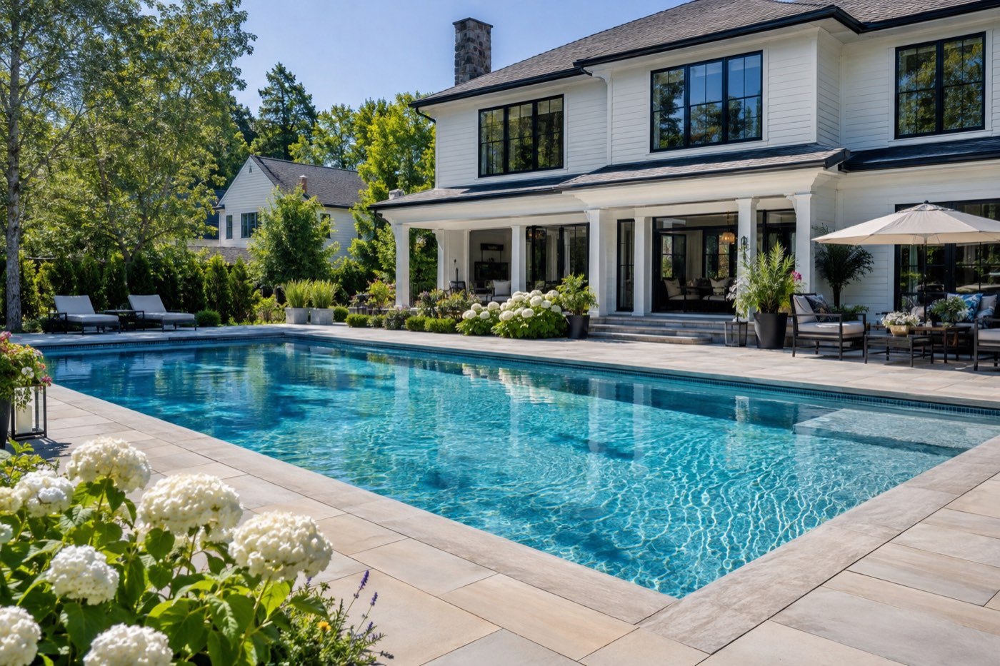A large residential pool with a spa spillover beside a modern home